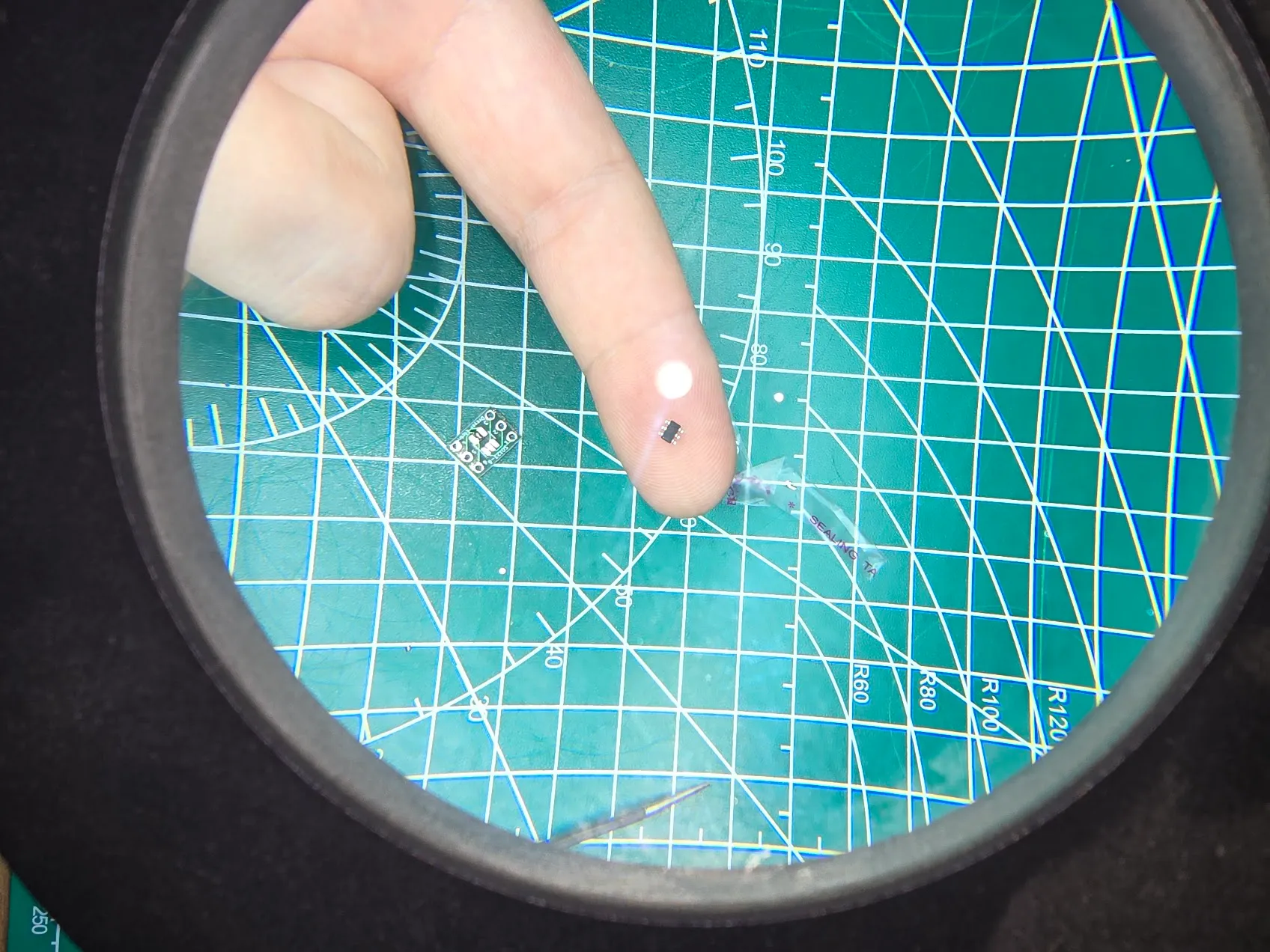 ATtiny10 microcontroller chip viewed through a loupe next to a small breakout board