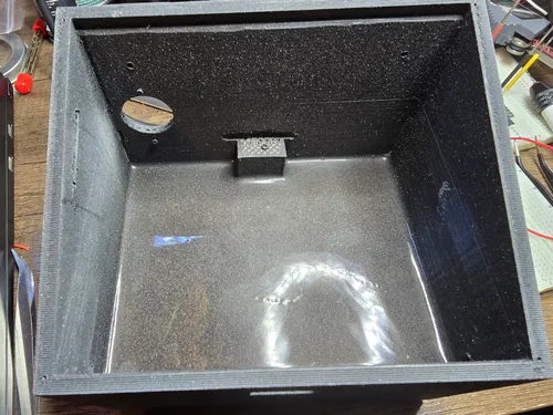 Inside of the printed enclosure, with steel shot set in a glossy pour of epoxy across the floor