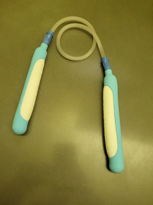 A pair of teal PureWick urine-collection devices connected by suction tubing, arranged like nunchucks