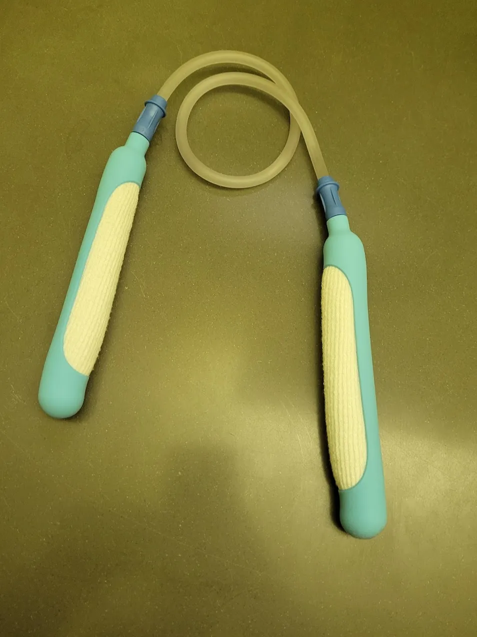 A pair of teal PureWick urine-collection devices connected by suction tubing, arranged like nunchucks