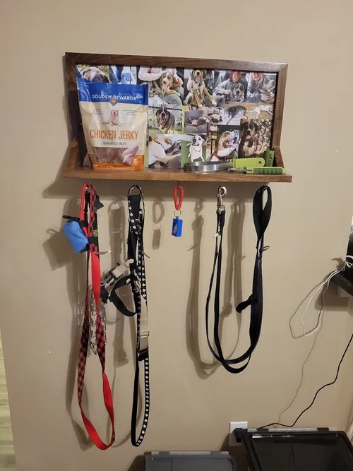 Finished walnut shelf mounted on the wall with a dog photo collage, treats, and leashes hanging from hooks