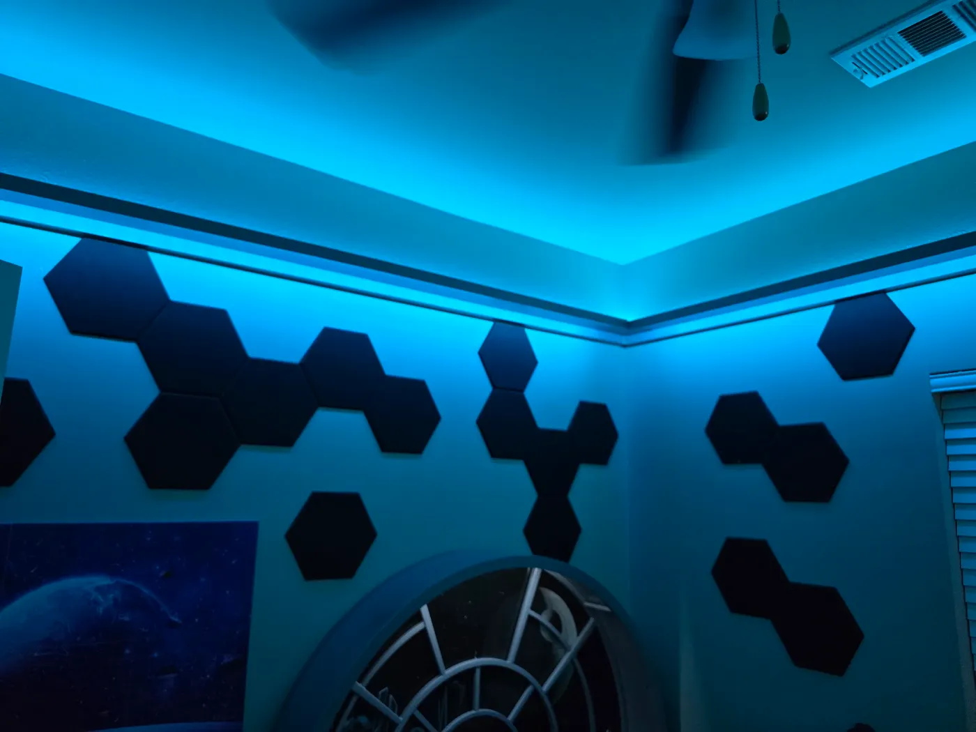 Hexagonal acoustic tiles on the wall near a glowing LED-lit ceiling corner in a Star Wars-themed bedroom