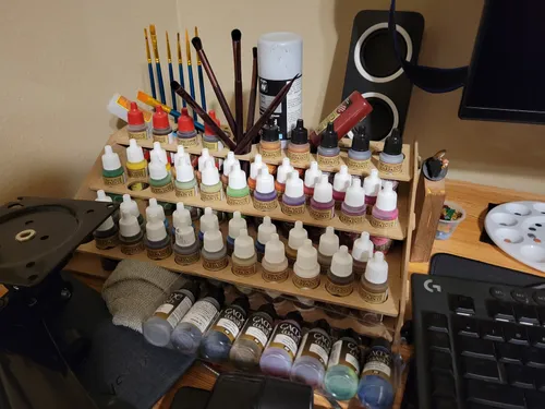 Old tiered wooden paint holder packed full of paint bottles